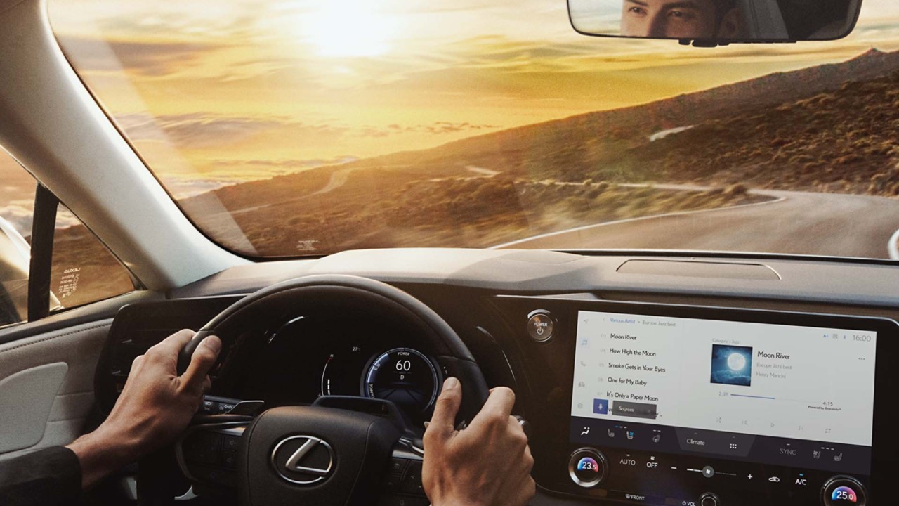 A person driving a Lexus RX on a coastal road 